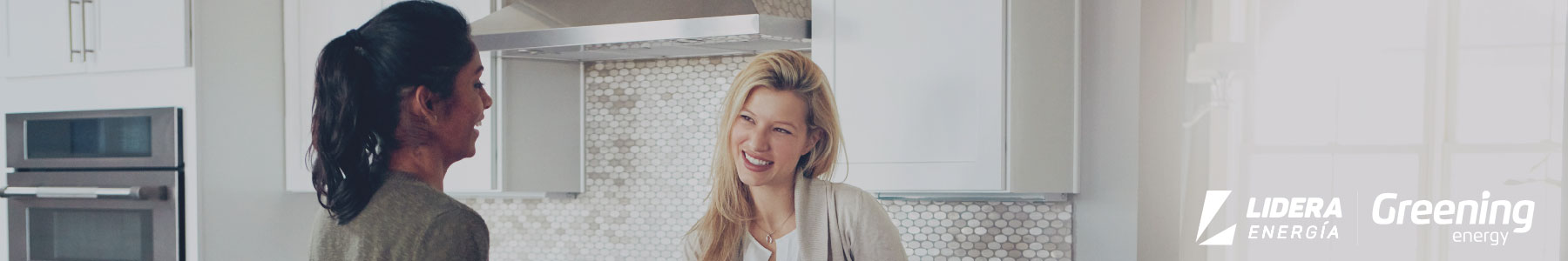 Dos mujeres conversan en una cocina moderna y luminosa, disfrutando del confort de un hogar energéticamente eficiente.